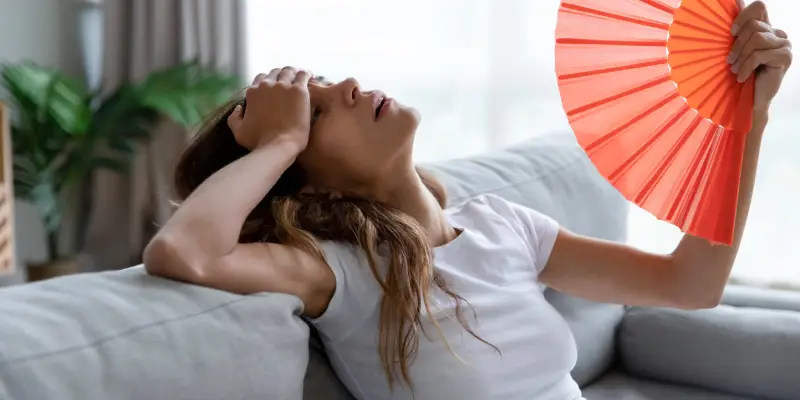 woman-fanning-herself-in-hot-room